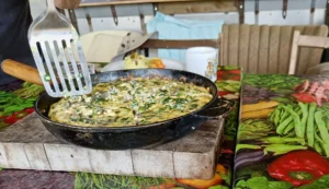Egg and spinach frittata in a frying pan with a fish slice cutting in