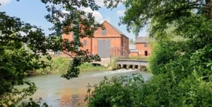 Red brick building on the other side of a river next to a bridge