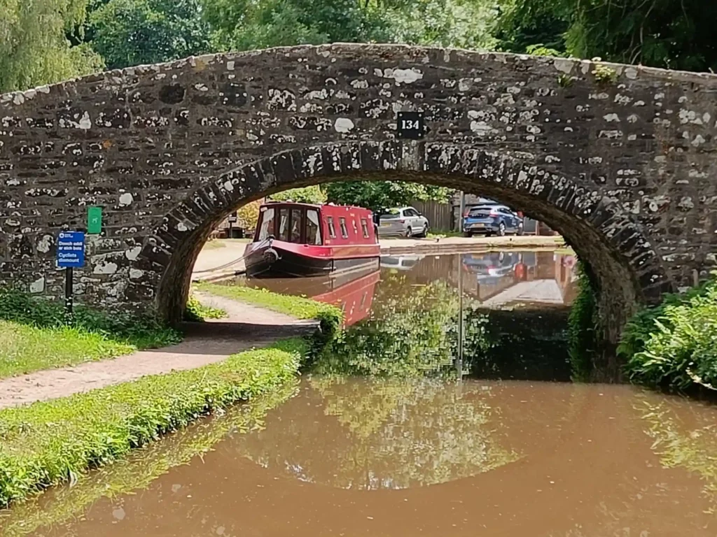 Bridge over canal with a moored red canal boat visible on other side