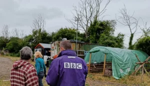 Man in BBC jacket standing next to lady in front of polytunnel