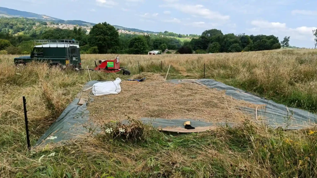 A tarpaulin with raked seed, a new unsieved load dropped at the end and the harvester driving away