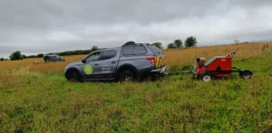 Two vehicles pulling seed harvesters setting off to harvest a field