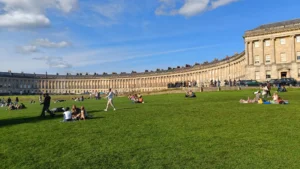 Large Crescent building with green in front full of people
