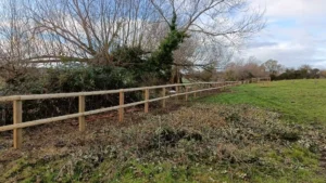A newly installed two rail stock fence running along a field edge