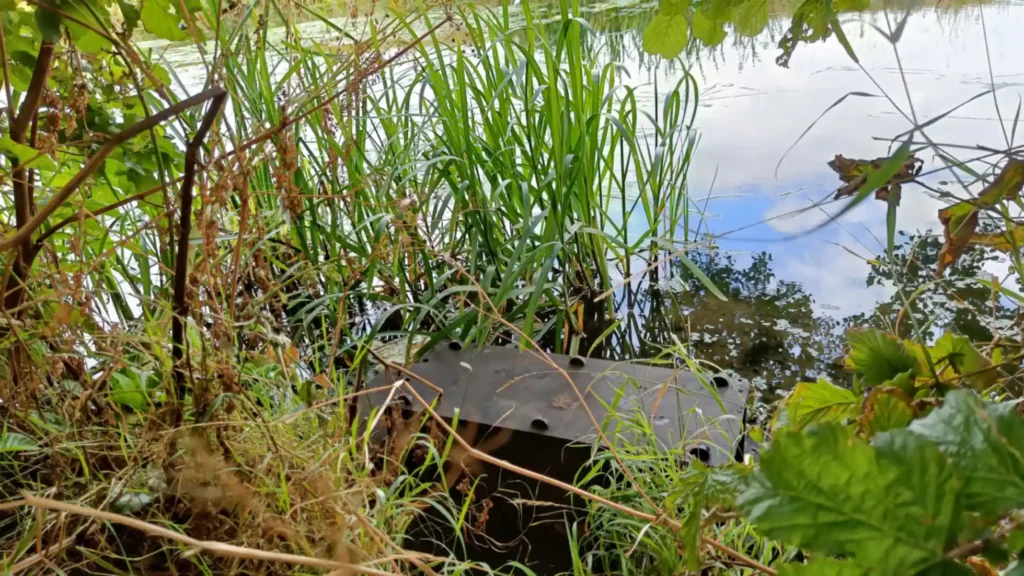 A monitoring raft moored to the side of the river bank, surrounded by vegetation