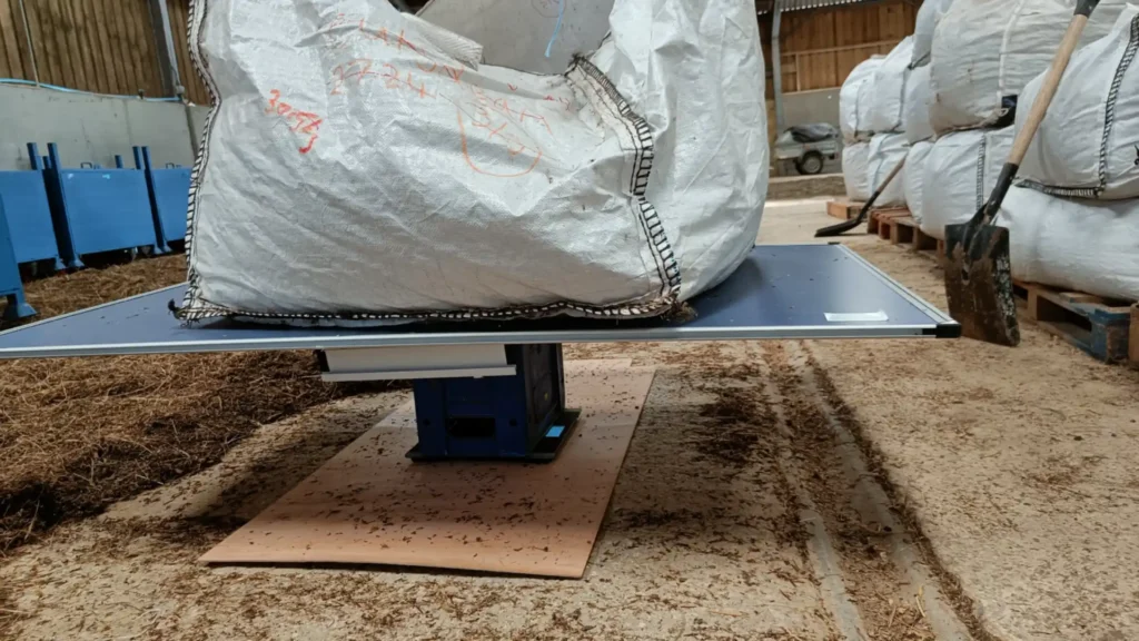 A large ton bag on a board, crate and weighing scales