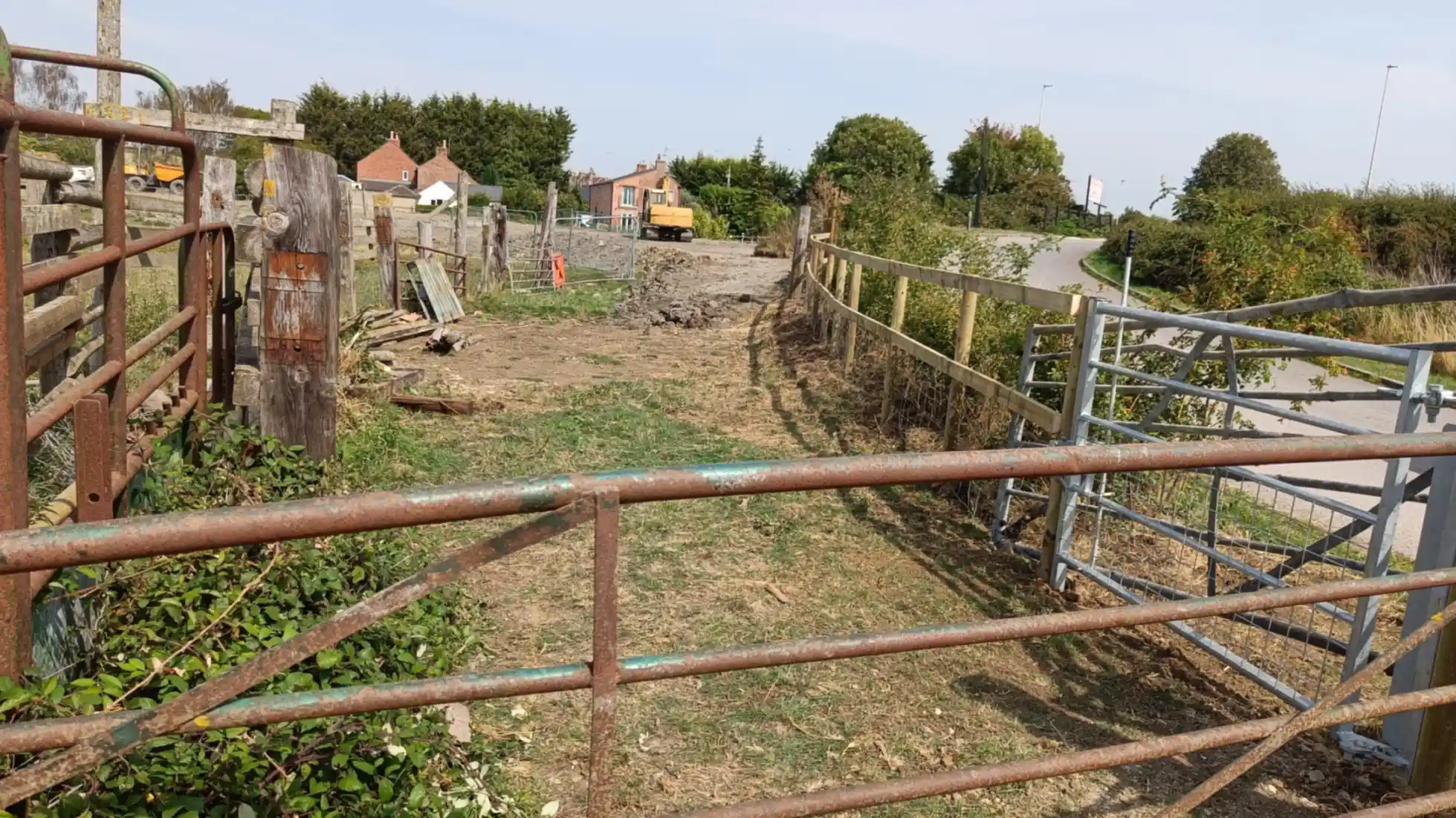 An old gate in the foreground and new fence and gate to the right