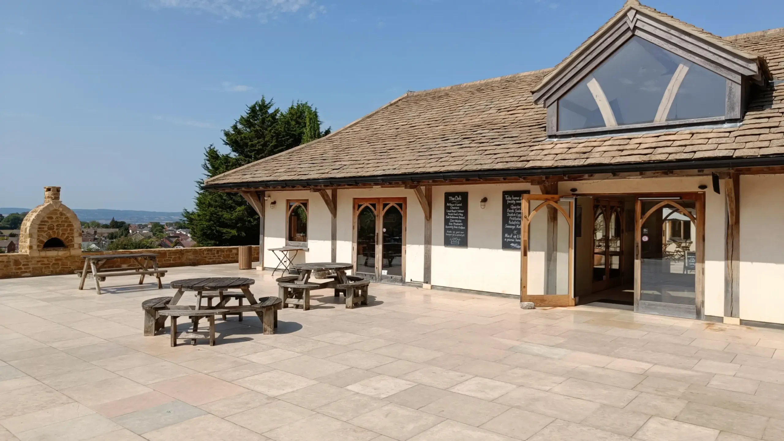 A single story shop with large terrace in front with picnic tables
