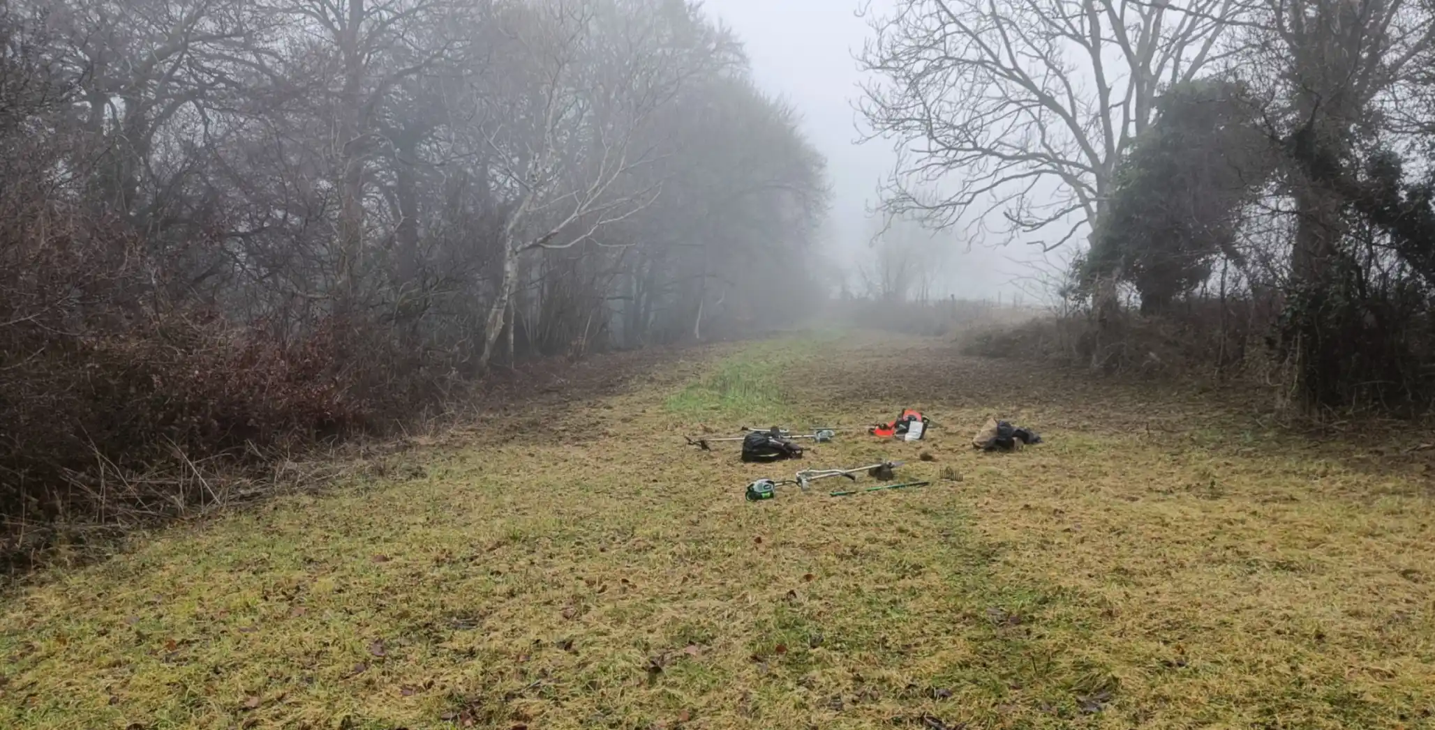 Misty view of a grassland which has been cut and raked. brush cutting equipment laying on the floor in the middle